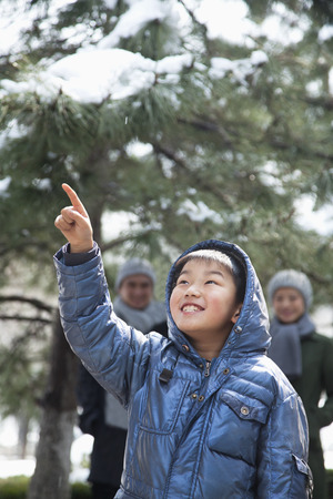 Boy pointing up with parents on the backgroundの写真素材
