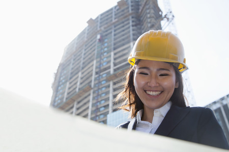 Young architect looking down at blueprint outdoorsの写真素材