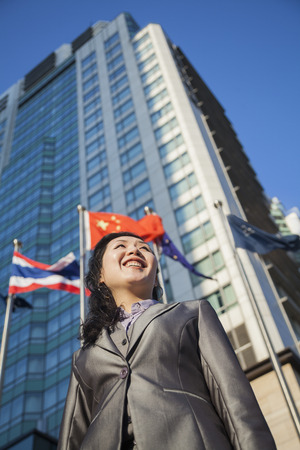 Low angle view of businesswoman in front of a building with Chinese flag in the backgroundの写真素材