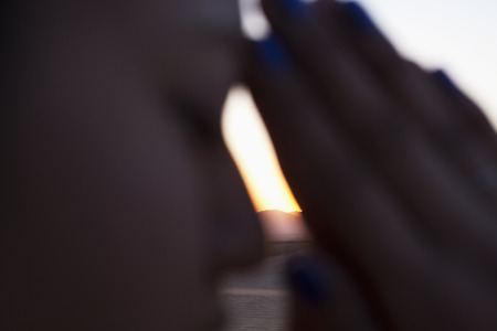 Serene young woman with eyes closed and hands together in prayer pose in the desert in China, side view, extreme close upの写真素材