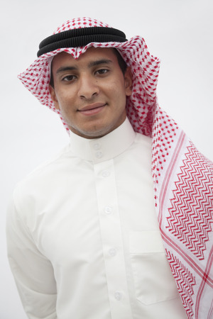 Portrait of smiling teenage boy in traditional Arab clothing, studio shotの写真素材