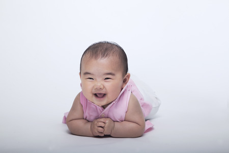 Portrait of smiling and laughing baby lying down, studio shot, white backgroundの写真素材