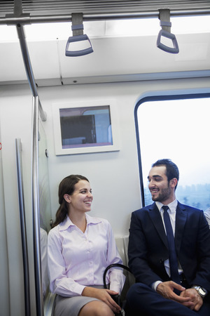 Two young business people sitting and chatting on the subwayの写真素材