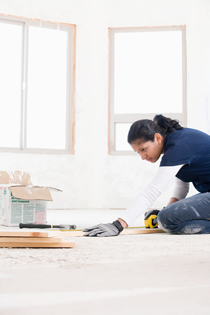 A female builder measuring a plank of woodの写真素材