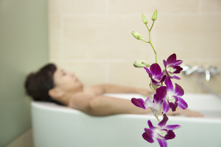 Woman Bathing with Orchid in Foregroundの写真素材