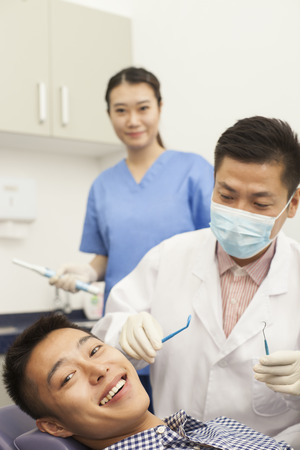 Male Dentist Examining Male Patientの写真素材