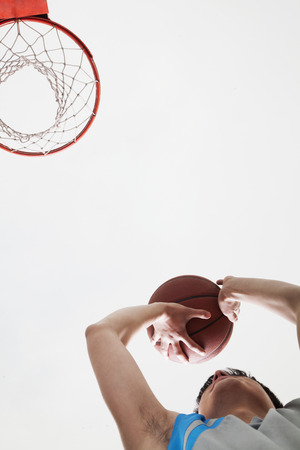 Man attempting to through basketball in to the basket の写真素材