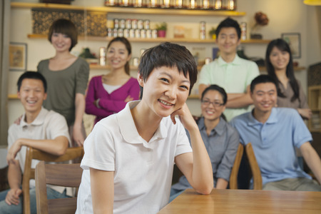 Portrait of young woman with group of friends at a coffee shopの写真素材