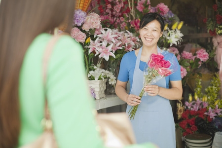 Florist Giving Bunch Of Flowers To Customerの写真素材
