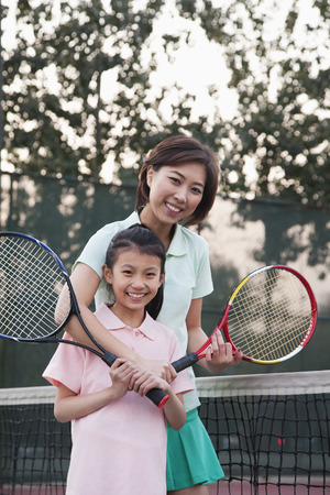 Mother and daughter playing tennis, portrait の写真素材