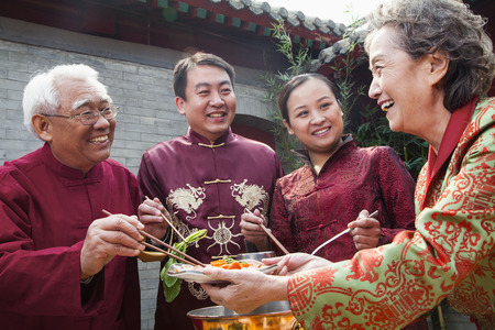 Family enjoying Chinese meal in traditional Chinese clothingの写真素材