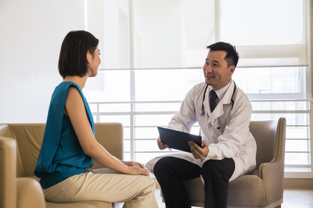 Doctor sitting down and consulting patient in the hospitalの写真素材