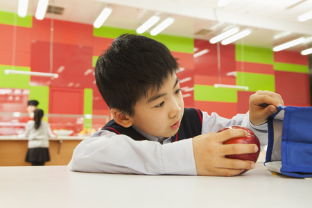 School boy checking lunch bag in school cafeteriaの写真素材
