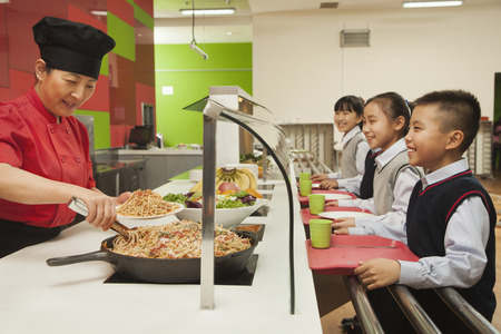 School children standing in line in school cafeteriaの写真素材