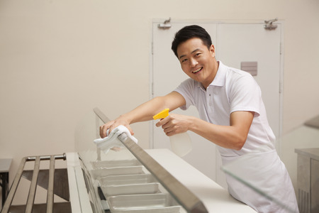 Cafeteria worker cleaning food serving areaの写真素材