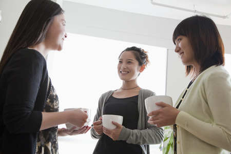 Three businesswomen on the coffee break in the officeの写真素材