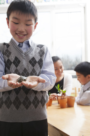 Schoolboy holding a little turtle in his hands, Beijingの写真素材