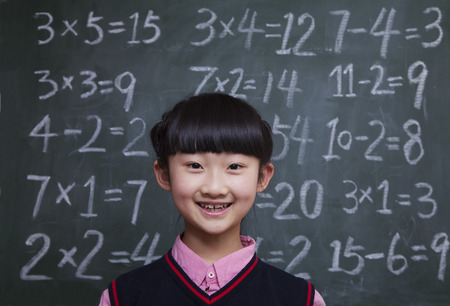 Portrait of schoolgirl in front of blackboard with math equationsの写真素材