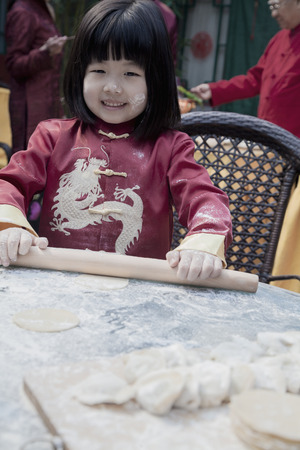 Portrait of little girl making dumplings in traditional clothingの写真素材