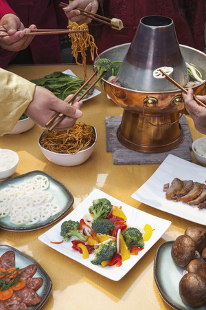 Family eating Chinese hot pot, hands onlyの写真素材