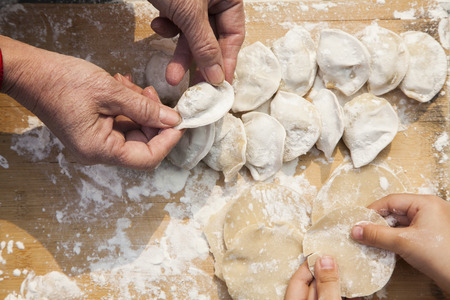 Senior woman and girl making dumplings, hands onlyの写真素材