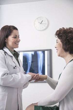 Young female doctor holding the hands of a patient の写真素材