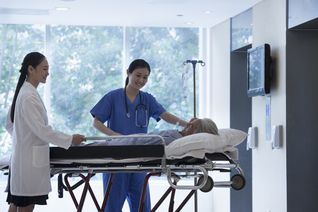 Female doctor and nurse wheeling a stretcher with a patient in the halls of the hospitalの写真素材