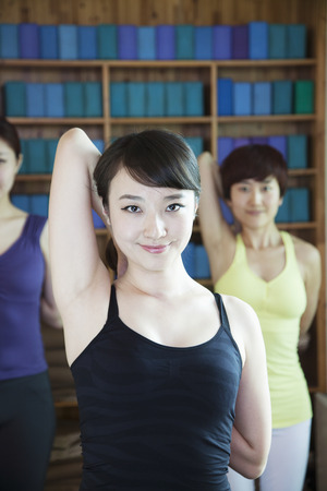Three young women stretching and doing yoga, looking at camera, の写真素材