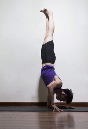Upside down man doing yoga in a yoga studio, side viewの写真素材
