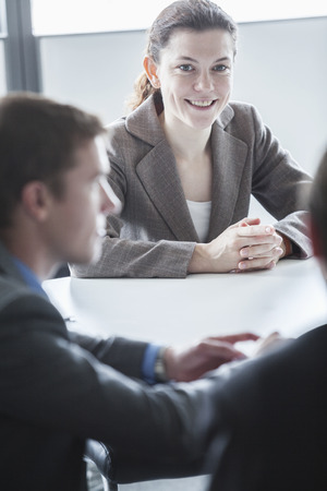 Three smiling business people sitting at a table and having a business meeting in the officeの写真素材