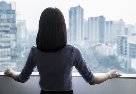 Rear view of a businesswoman looking out the window at the cityscape in Beijing, Chinaの写真素材