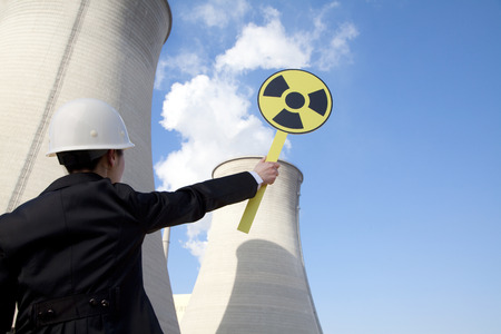 Engineer in front of cooling towers with sign