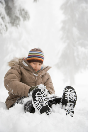 Boy sitting in the snowの写真素材