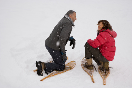 A couple crouching in the snow wearing snowshoesの写真素材