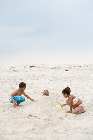 Children burying father in sandの写真素材