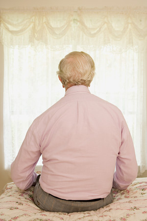 Elderly man sitting on a bedの写真素材