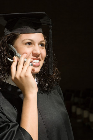 Female graduate using a cellular phoneの写真素材