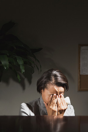 Businesswoman with her head in her handsの写真素材