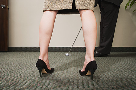 Man playing golf through woman's legsの写真素材