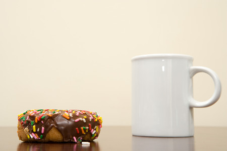 Coffee cup and doughnut on a deskの写真素材