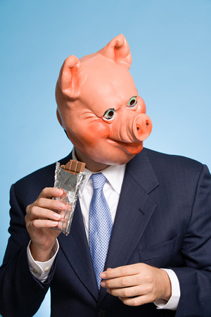 Man in a pig mask eating chocolateの写真素材