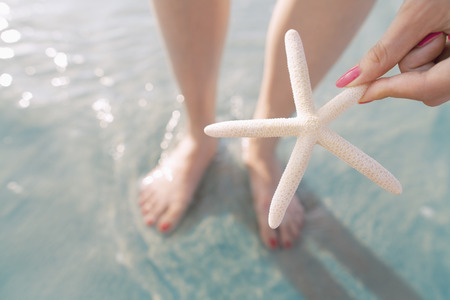 Woman holding starfish at the beachの写真素材