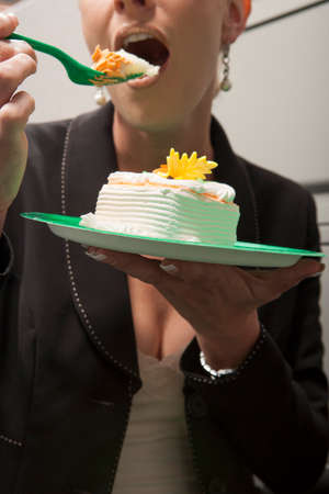 Business person eating birthday cake in cubicleの写真素材