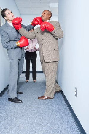 Businessmen fighting in officeの写真素材