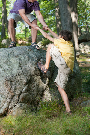 Father and son climbing on rock together in natureの写真素材