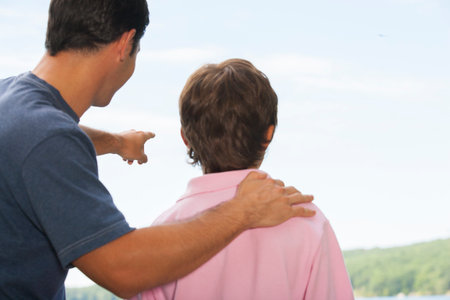 Father and son pointing at lake togetherの写真素材