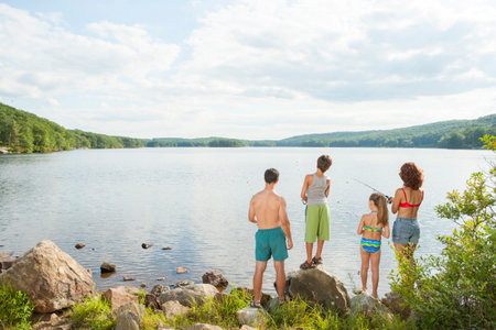 Family fishing together at lake shoreの写真素材