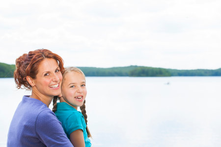 Mother and daughter together in nature at lakeの写真素材