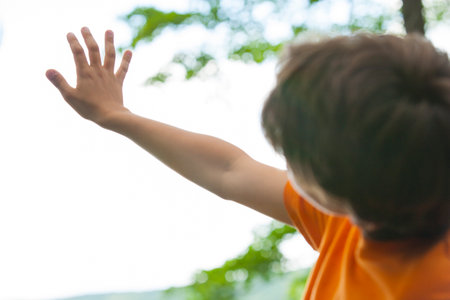 Boy holding hand up in natureの写真素材