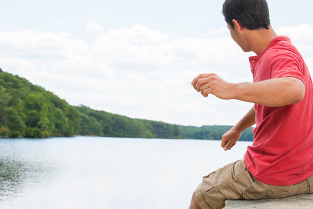 Man skipping rocks at lakeの写真素材